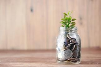 a glass jar filled with coins and a plant by Towfiqu barbhuiya courtesy of Unsplash.